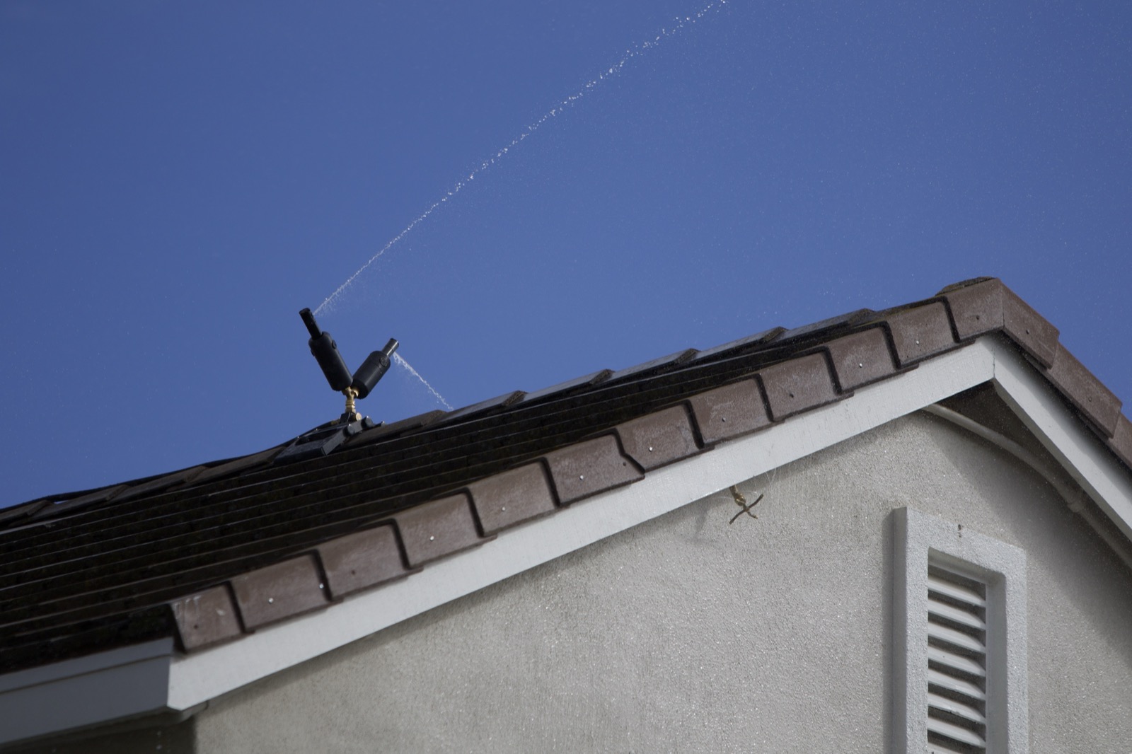 Roof and eave wildfire sprinklers spraying around a structure