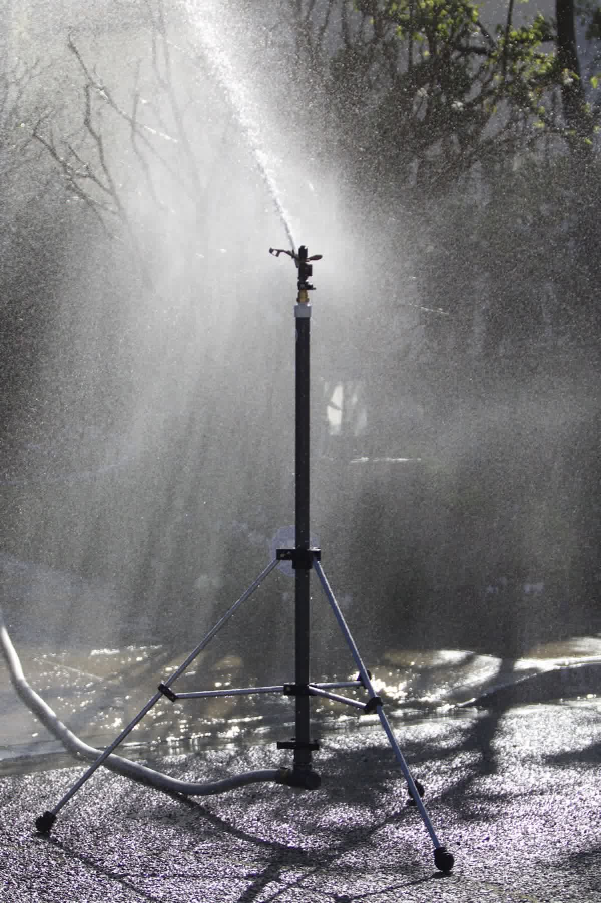 Attack tripod sprinkler delivering targeted zone defense around a property