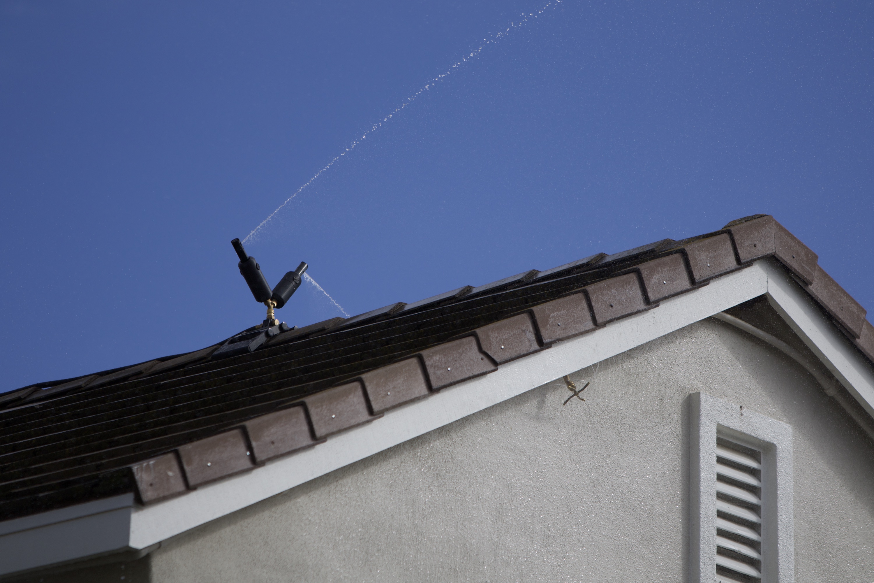 Roof and eave sprinklers spraying around a home
